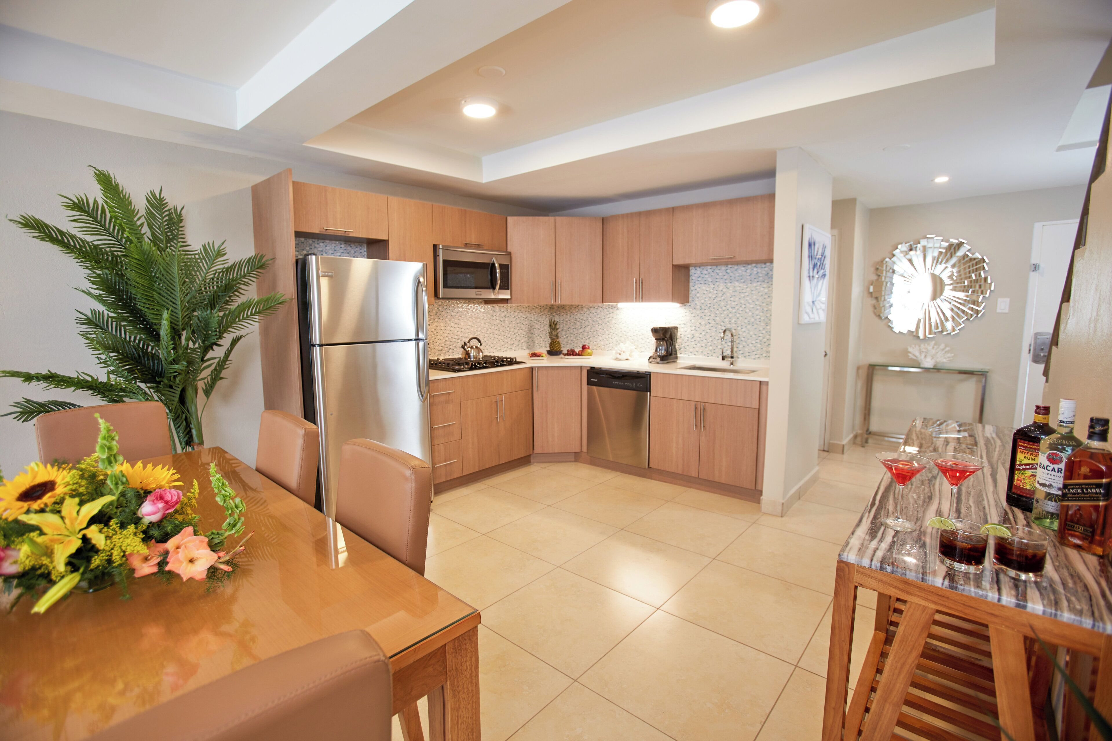 A modern kitchen with wooden cabinets, stainless steel appliances, and a dining area with a table set for two.
