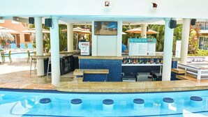 A pool area with a bar, lounge chairs, and umbrellas. - Divi Dutch Village Beach Resort (Oranjestad)