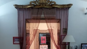 Un hall de hotel con mostrador de recepción, un tablón de anuncios y una escalera que sube a otro piso.