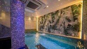 Una piscina con un mural tropical, un muro de azulejos e iluminación empotrada en el techo.