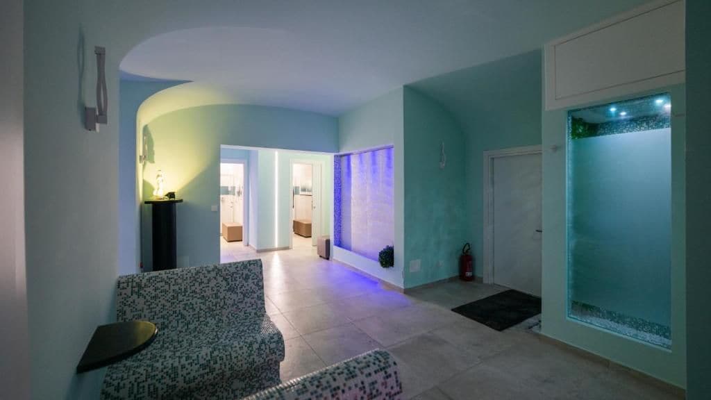 A spacious hallway with a patterned sofa, a small table, and a wall-mounted light fixture.