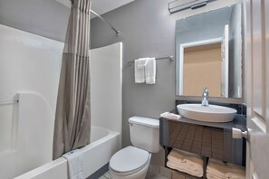 Bathroom features a bathtub, toilet, and sink with a mirror.