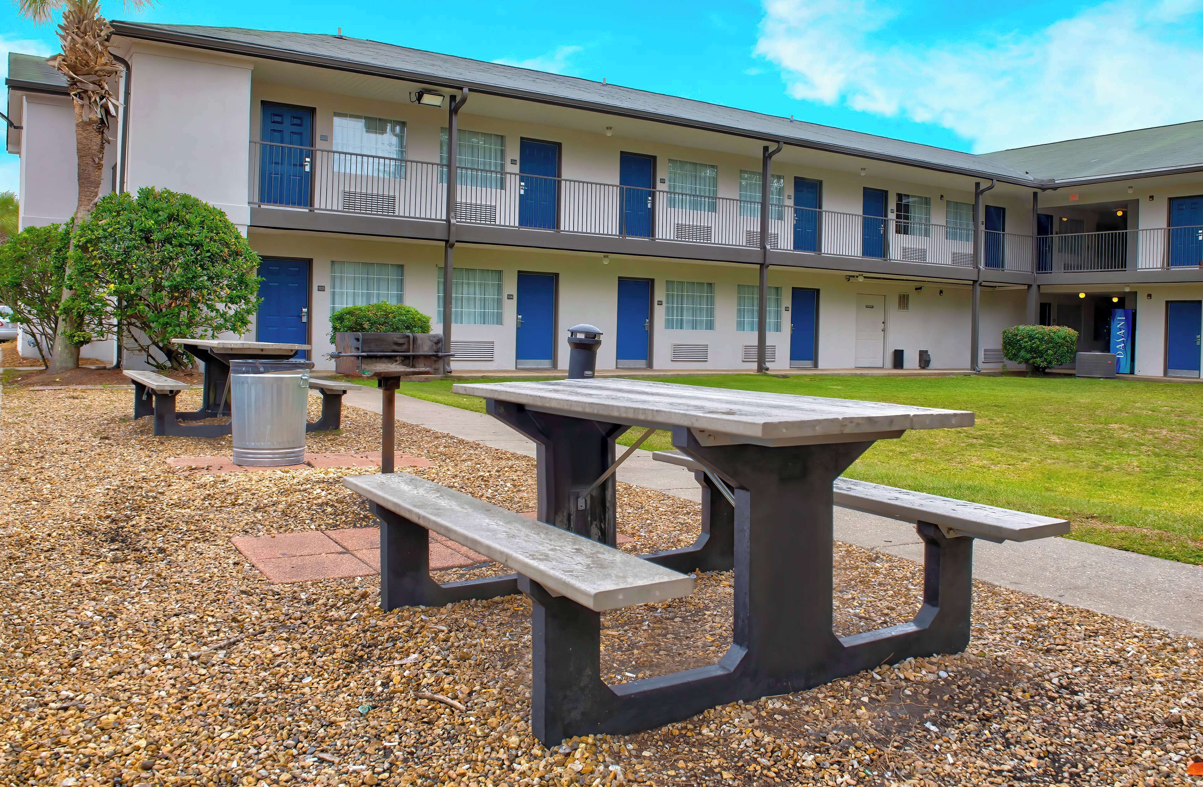 A motel with multiple balconies, outdoor seating, and a well-maintained lawn.