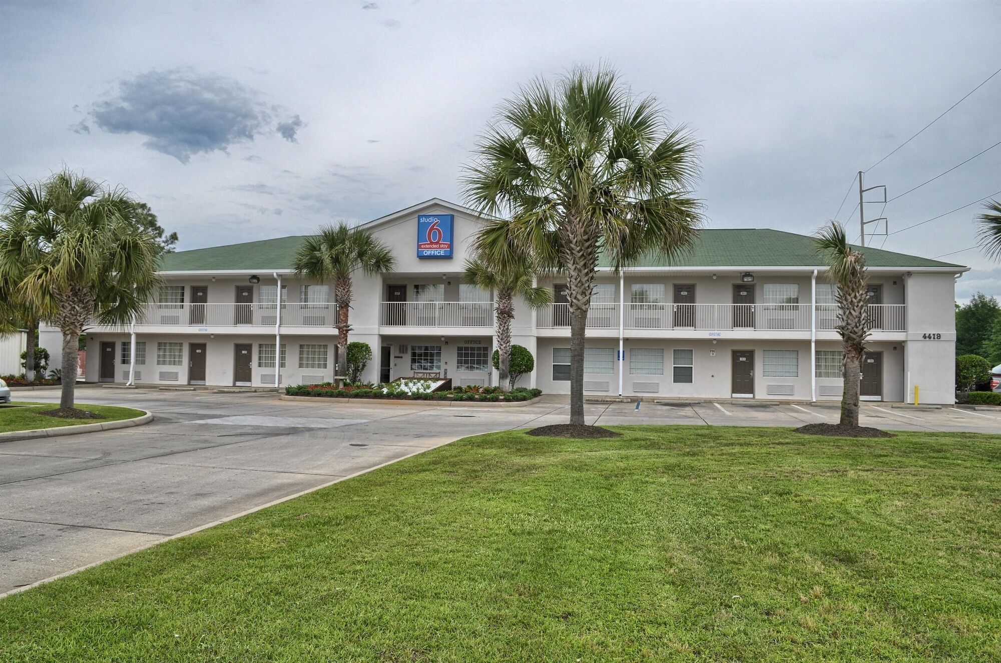 A two-story motel with a green roof and a blue sign indicating it has 6 rooms.