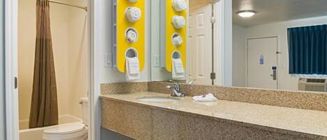 Un baño con encimera de granito, lavabo blanco y un espejo con dispensadores de toallas amarillos.