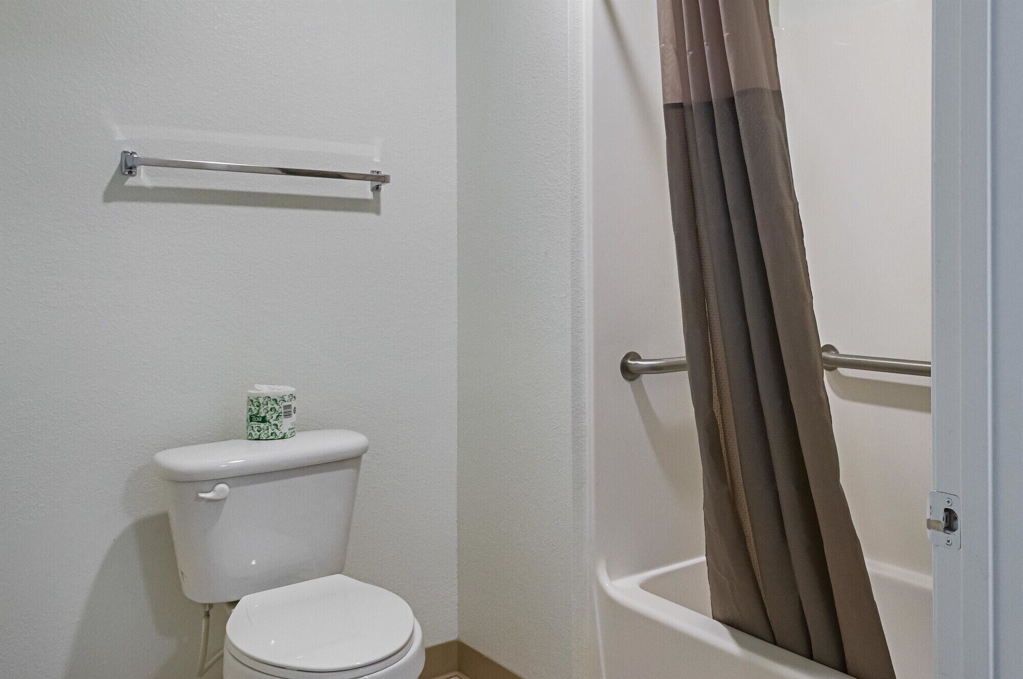 A bathroom with a toilet, a towel rack, and a shower curtain.