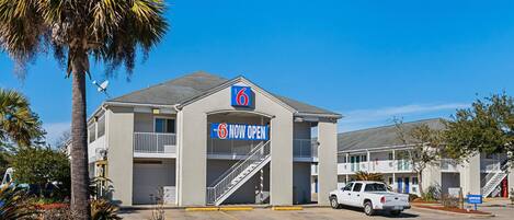 A motel with a '6' sign, a covered parking area, and a white pickup truck parked in front.