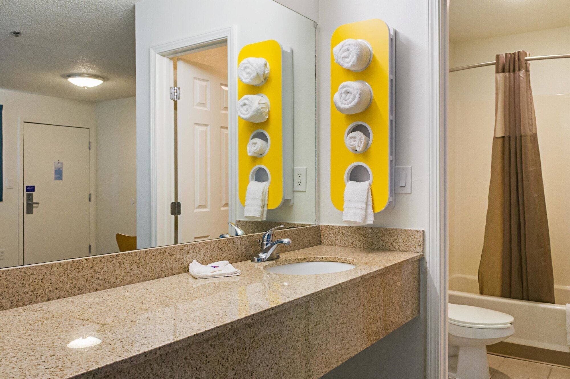 Un baño con encimera de granito, un lavabo, un espejo y una cortina de ducha.