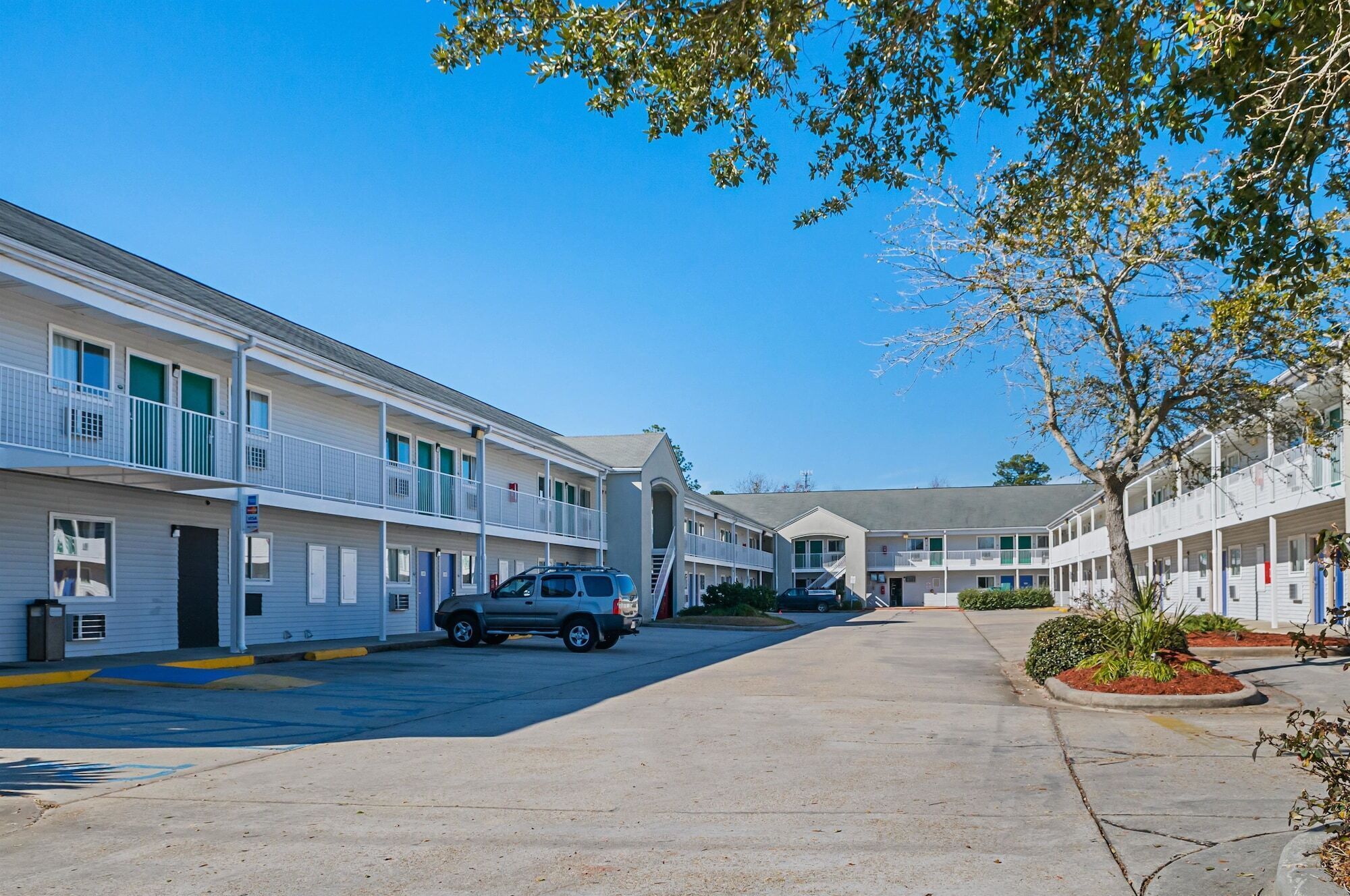A row of motel buildings with a central parking area.