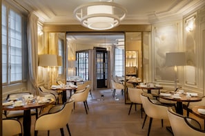 A hotel dining area with multiple tables, chairs, and chandeliers. - Hôtel Elysia by Inwood Hotels (Paris)