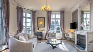 A spacious living room with a sofa, a coffee table, a fireplace, and a television. - Hôtel Elysia by Inwood Hotels (Paris)