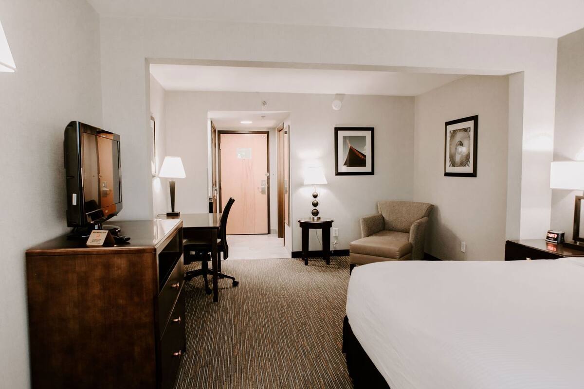Een hotelkamer met een bed, bureau, stoel, lamp en een televisie.