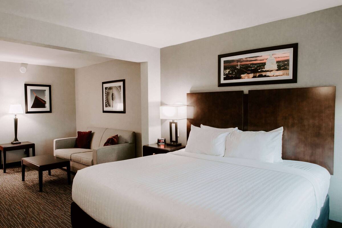 Een hotelkamer met een groot bed, een bank, een bureau en een nachtkastje.