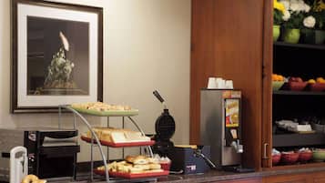 A breakfast buffet with a waffle maker, toaster, and various food items.
