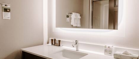 Un baño moderno con un lavabo blanco, un espejo y un perchero para toallas.