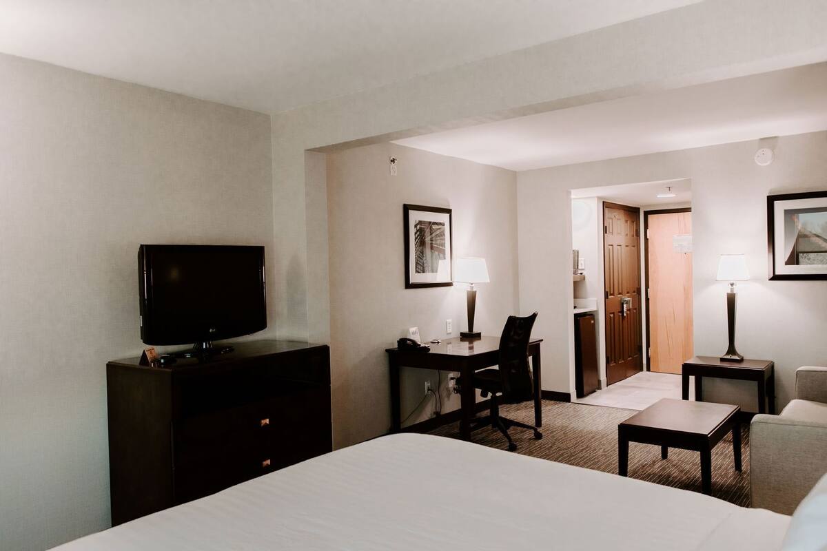 Een hotelkamer met een bed, een bureau, een stoel, een televisietoestel en een lamp.