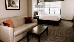 A hotel room with a bed, a sofa, a coffee table, and a framed picture on the wall.