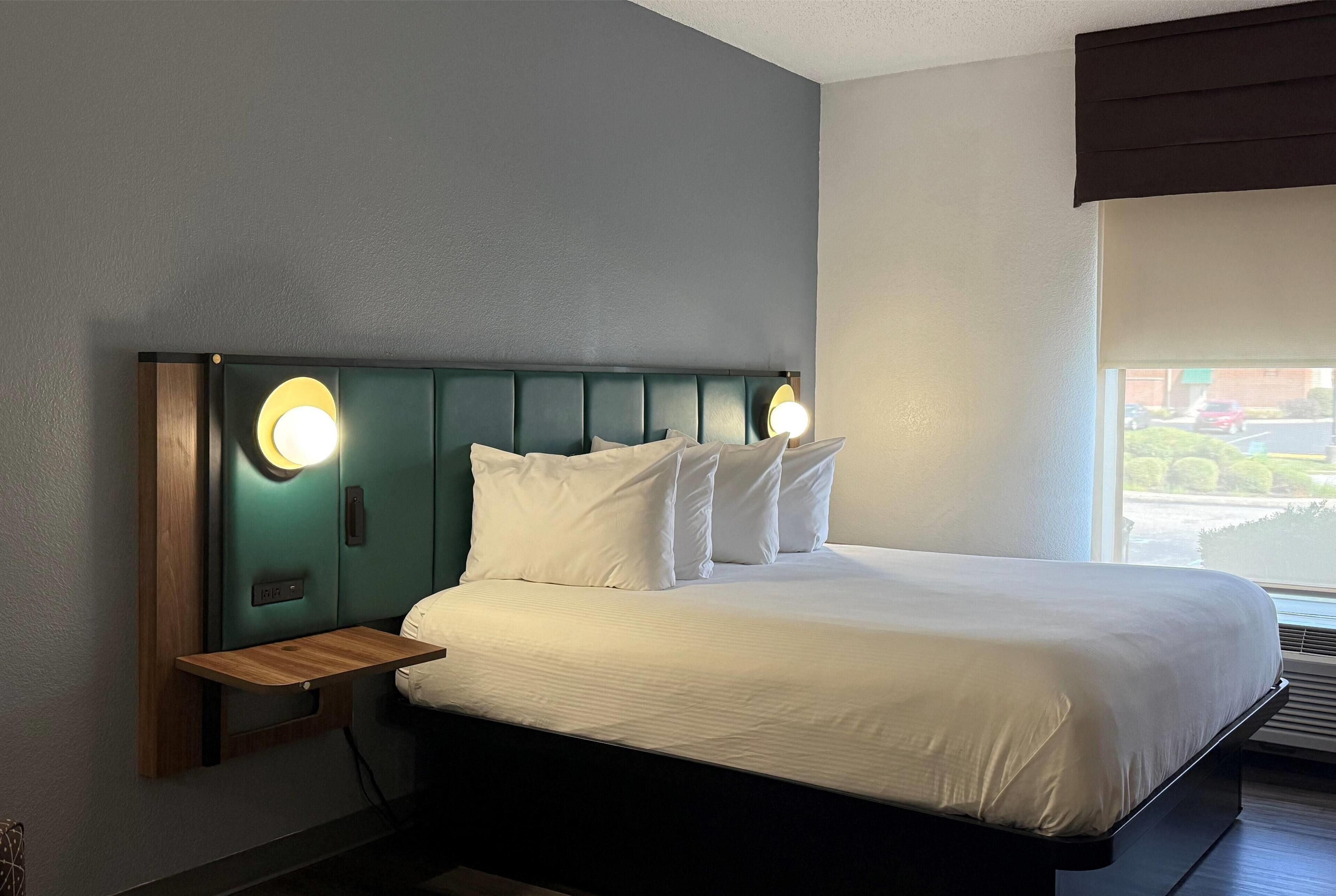 A neatly made bed with white linens and a headboard with built-in lighting.