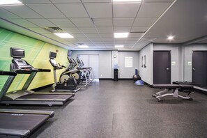 Een fitnessruimte met loopbanden, elliptische trainers en een gewichtbank.