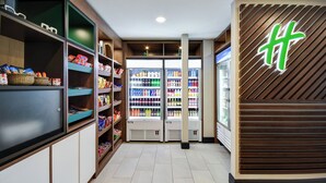 Un couloir bordé d’étagères remplies d’en-cas et de boissons, qui mène à un espace de présentation réfrigéré.