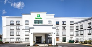 Een Holiday Inn hotel met een witte gevel, meerdere ramen en een helderblauwe lucht.