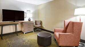 A hotel room with a flat-screen TV, a desk, a chair, a lamp, and a small ottoman. - Holiday Inn Allentown-Bethlehem by IHG (Allentown)