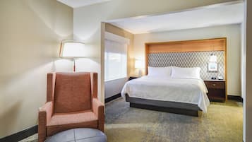Una habitación de hotel con una cama, una silla, una mesita de noche, una lámpara y una pared con un diseño decorativo.