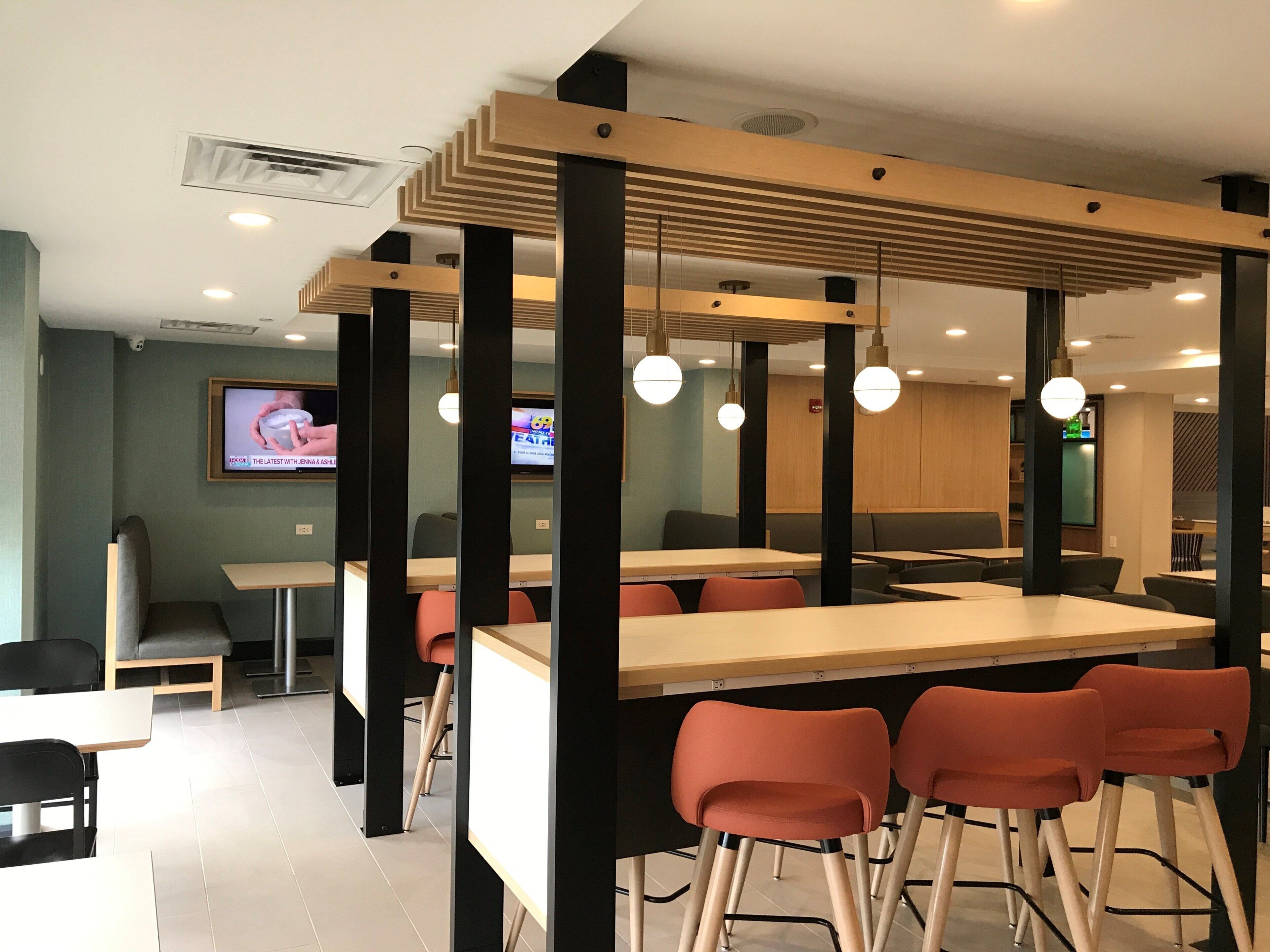 A modern dining area with high tables, chairs, and pendant lighting.