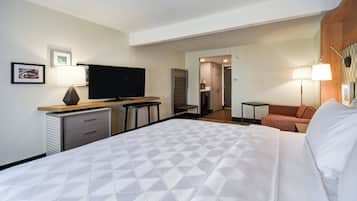 A hotel room with a bed, a desk, a television, a chair, and a small table.
