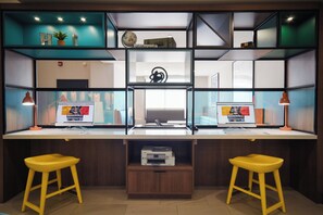 A modern workspace with two desks, each with a computer and a lamp, and two yellow stools. - Holiday Inn Allentown-Bethlehem by IHG (Allentown)