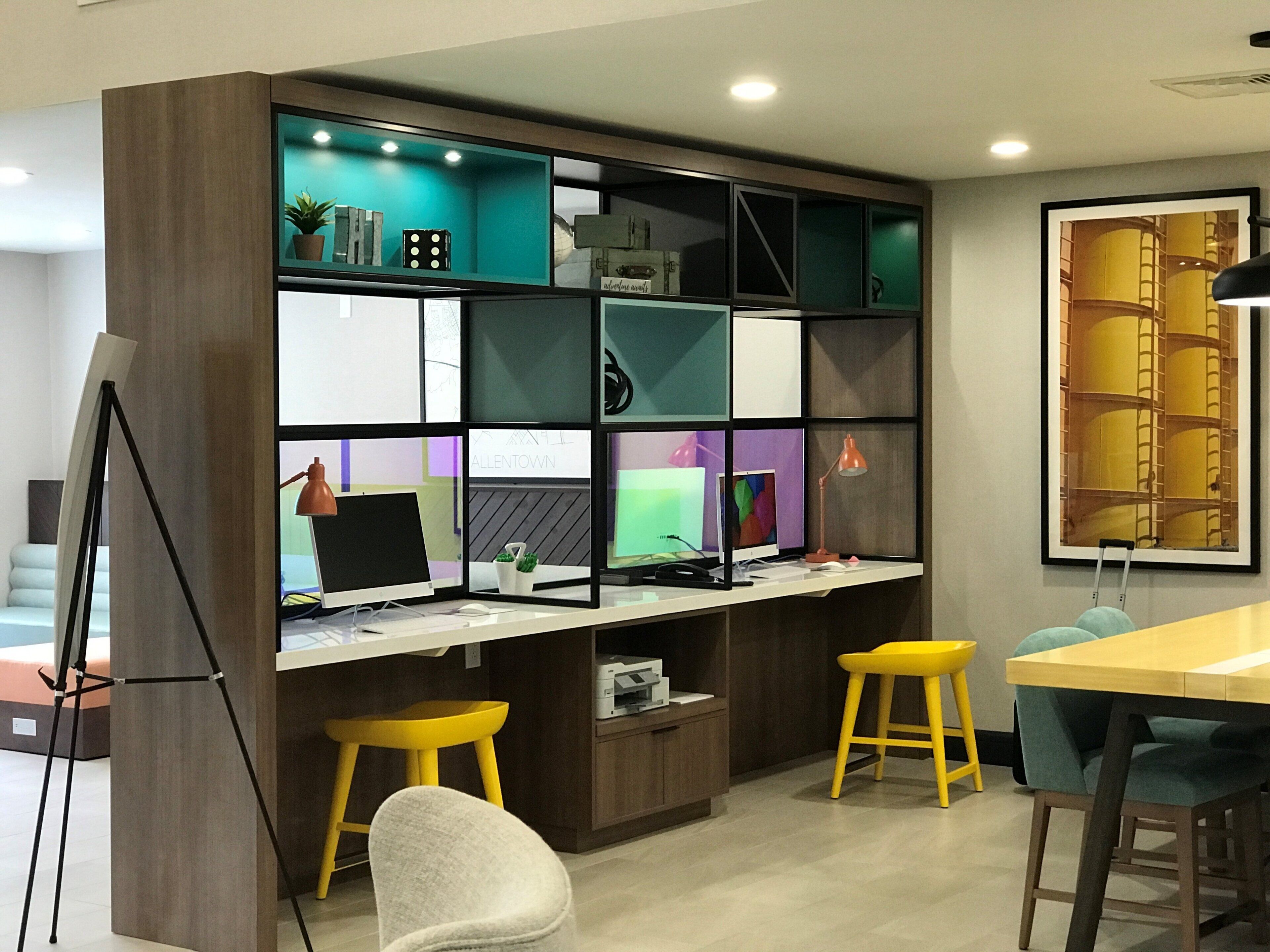 A modern office space with a desk, computer, and two yellow stools.