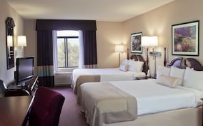 Ein Hotelzimmer mit zwei Betten, einem Schreibtisch, einem Fernseher und einem fenster mit Vorhängen.