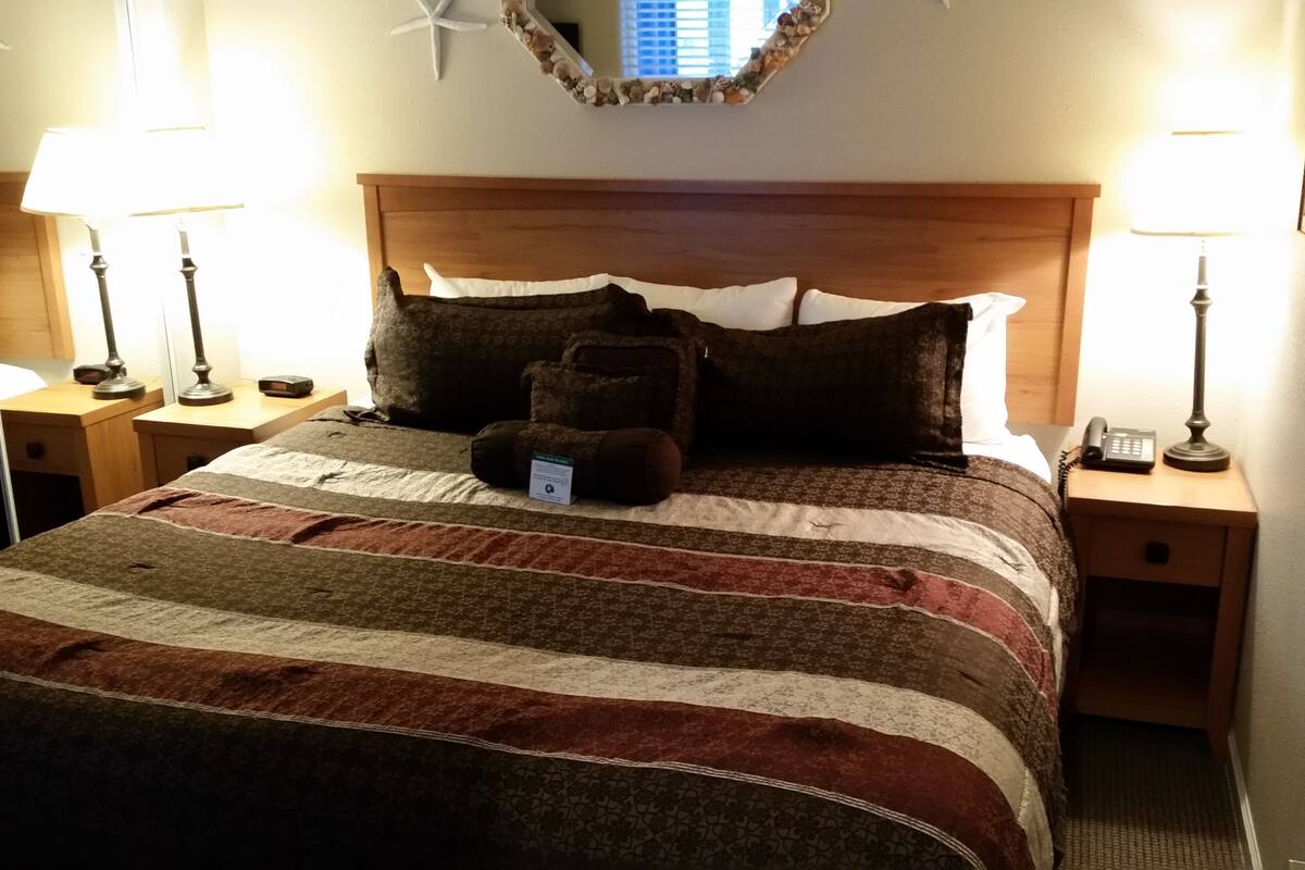 A neatly made bed with a striped blanket, two bedside lamps, and a starfish decoration on the wall.