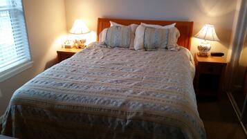 A neatly made bed with a patterned bedspread, two bedside lamps, and a wooden headboard.
