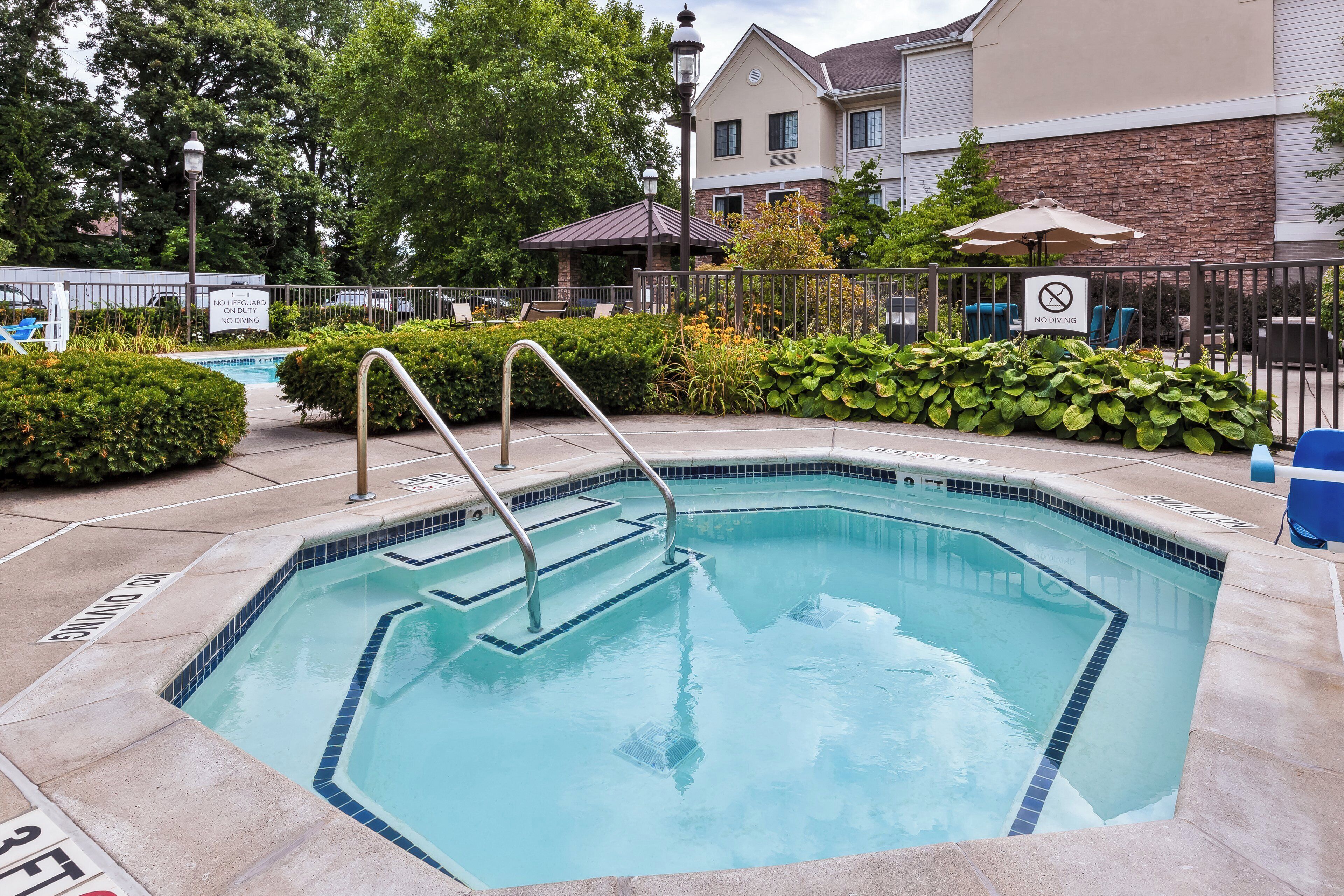 A swimming pool with a no diving sign, surrounded by a fence, and a lifeguard chair.