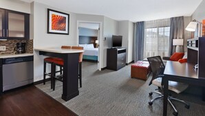 Una habitación de hotel con kitchenette, cama, escritorio y televisión.