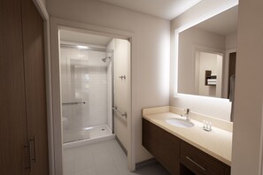 A modern bathroom with a glass-enclosed shower, a sink with a mirror, and wooden cabinetry. - Staybridge Suites Detroit-Utica by IHG (Utica)