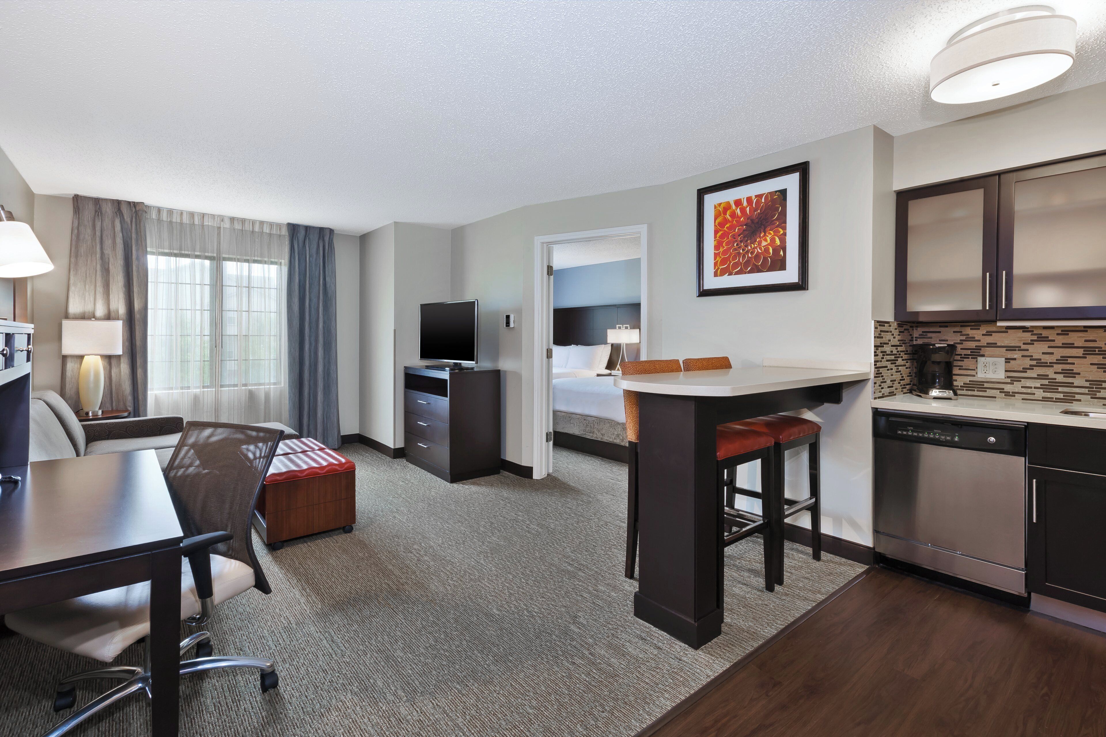 Une chambre d’hôtel équipée d’un bureau, d’une chaise, d’une kitchenette et d’un lit.