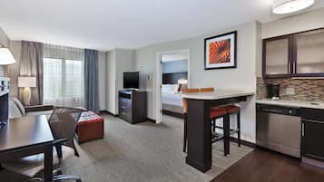 Une chambre d’hôtel équipée d’un bureau, d’une chaise, d’une kitchenette et d’un lit.