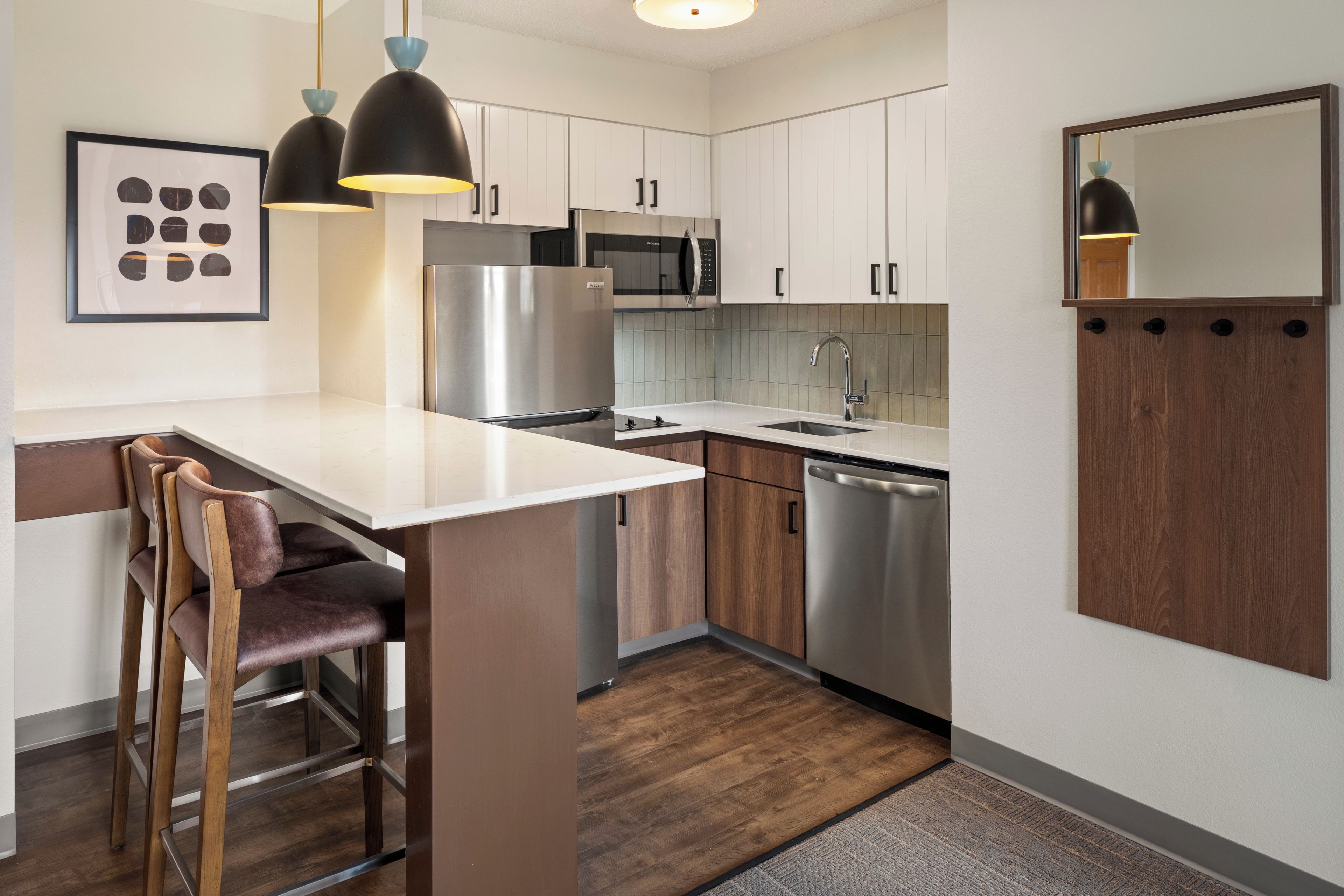 A modern kitchen with stainless steel appliances, wooden cabinets, and a bar area with stools.