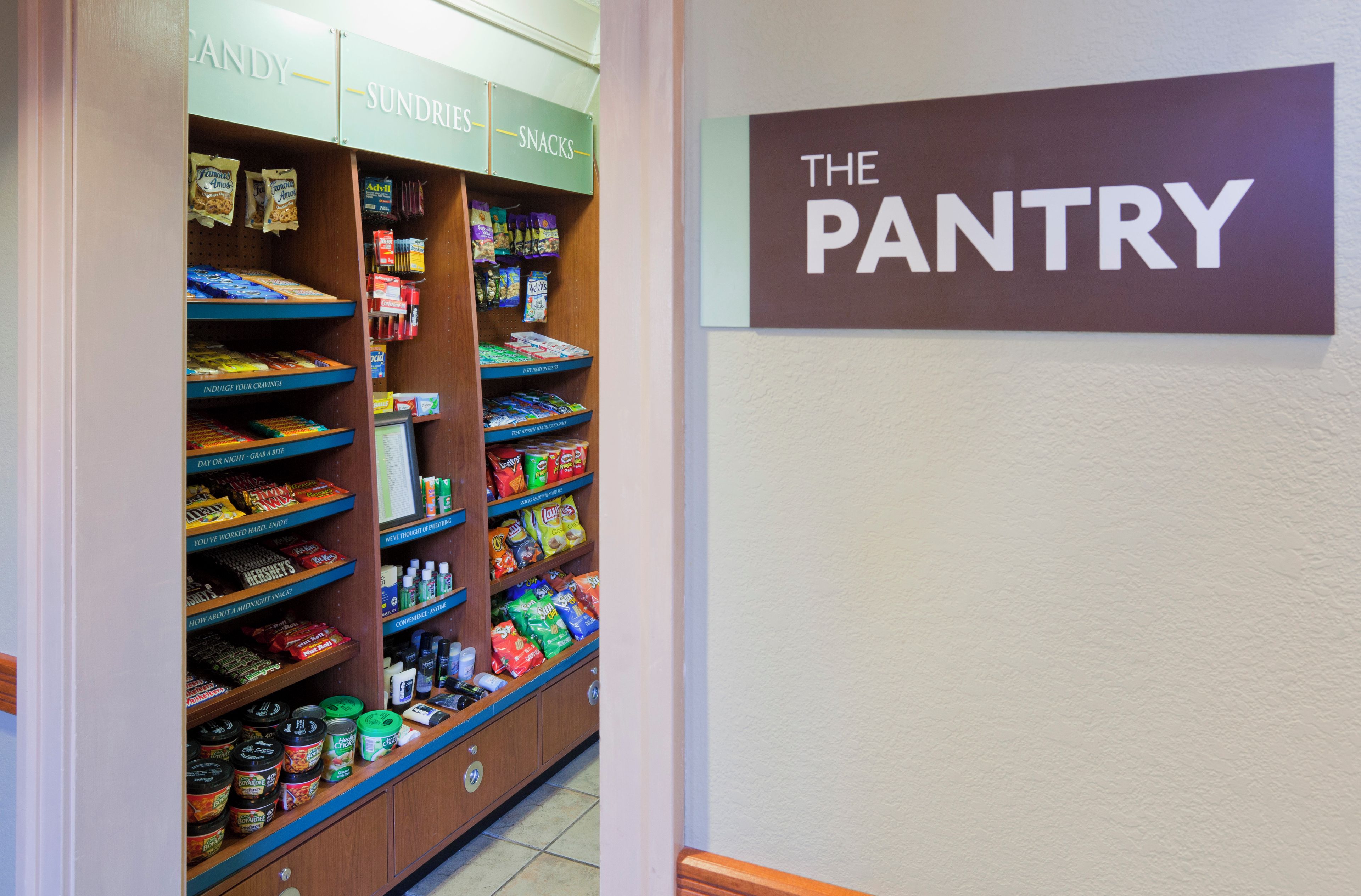 A pantry with shelves stocked with snacks, condiments, and canned goods.