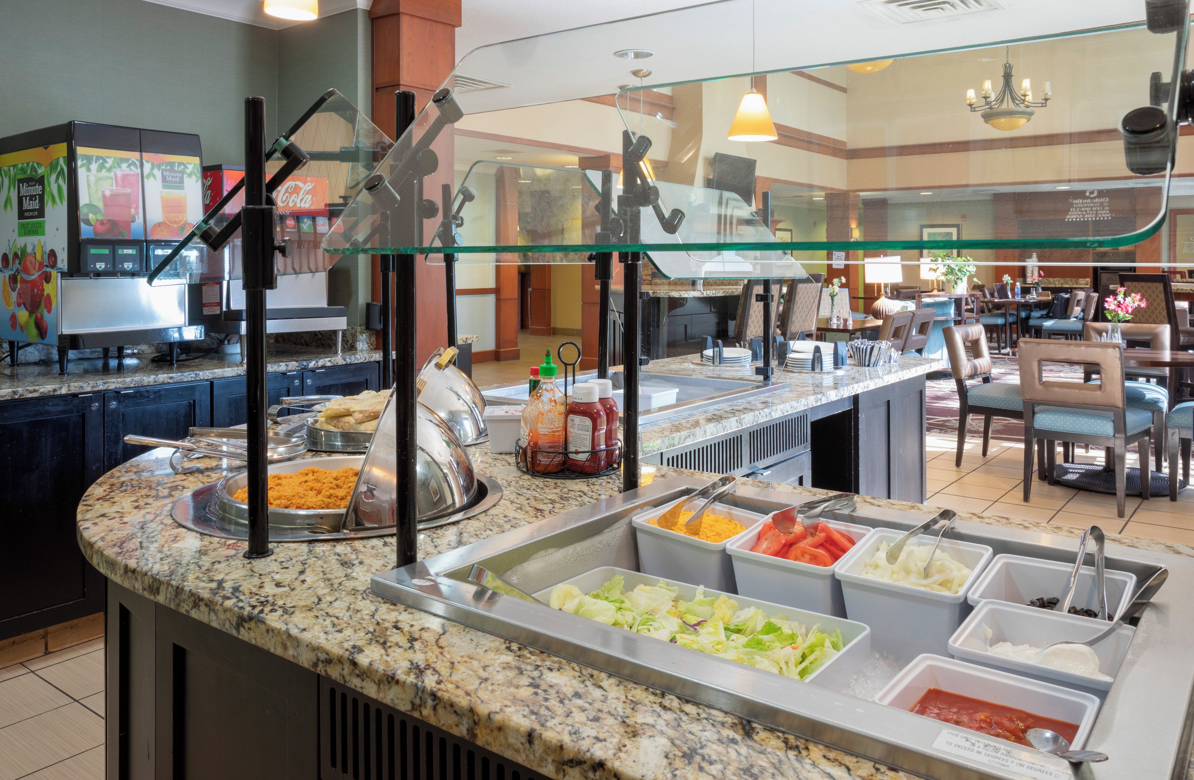 A buffet area with various food options, a coffee machine, and a seating area in the background.
