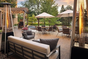 Un patio exterior con asientos, una chimenea y sombrillas.