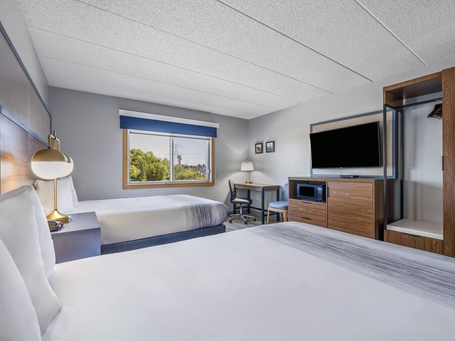 A hotel room with a bed, a desk, a TV, and a window with a view.