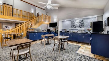 Cozinha espaçosa com escada de madeira, área de jantar com mesa e cadeiras, e ilha central com geladeira.
