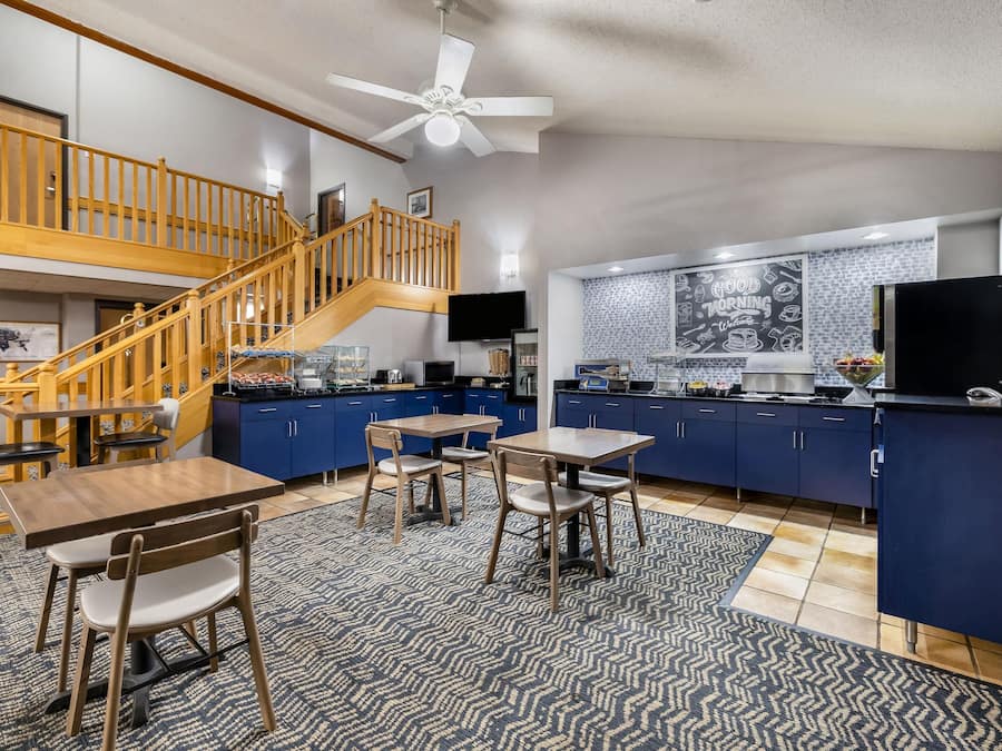 A spacious kitchen with a wooden staircase, a dining area with a table and chairs, and a kitchen island with a refrigerator.
