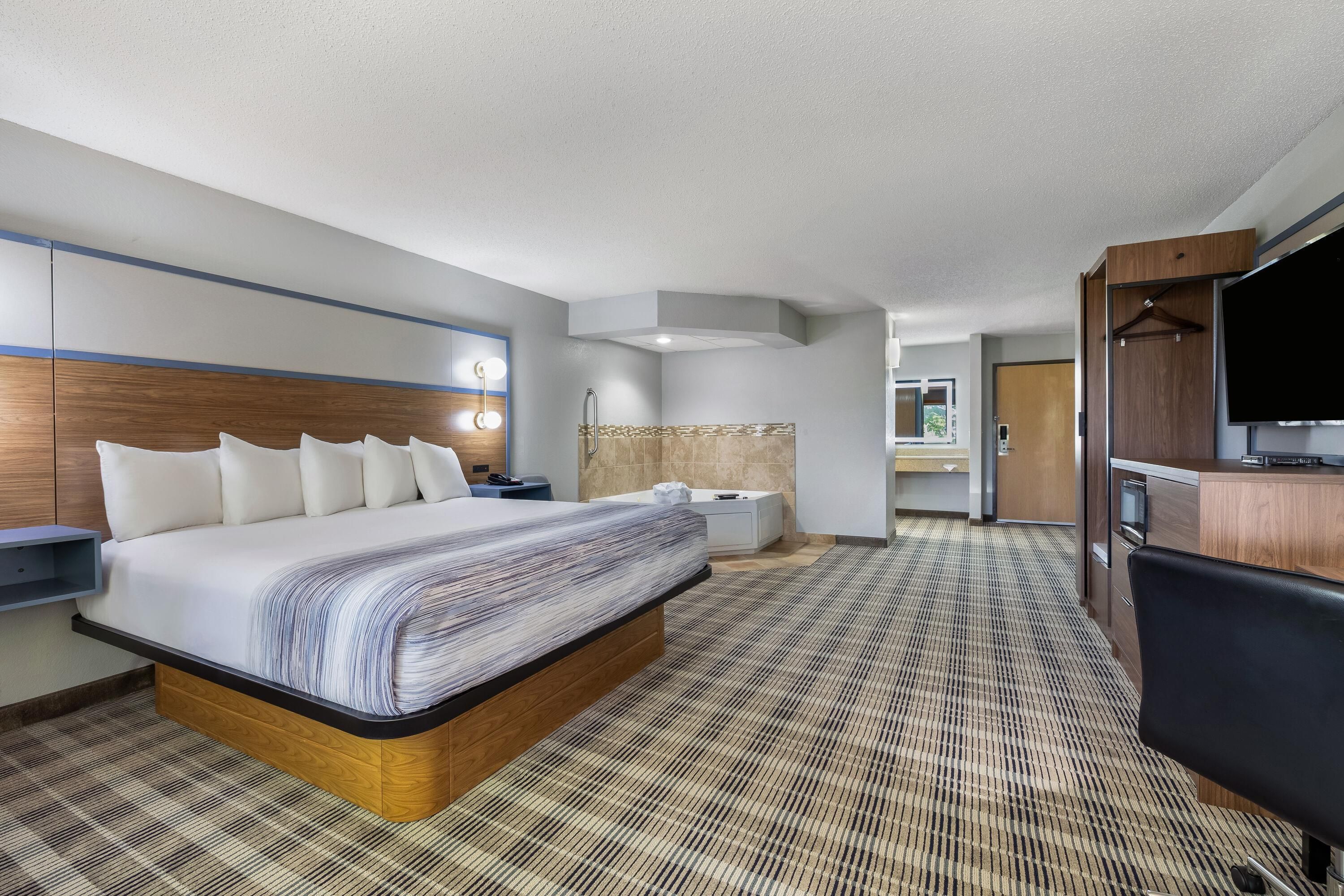 Una habitación de hotel con una cama grande, un escritorio, un televisor y un baño.
