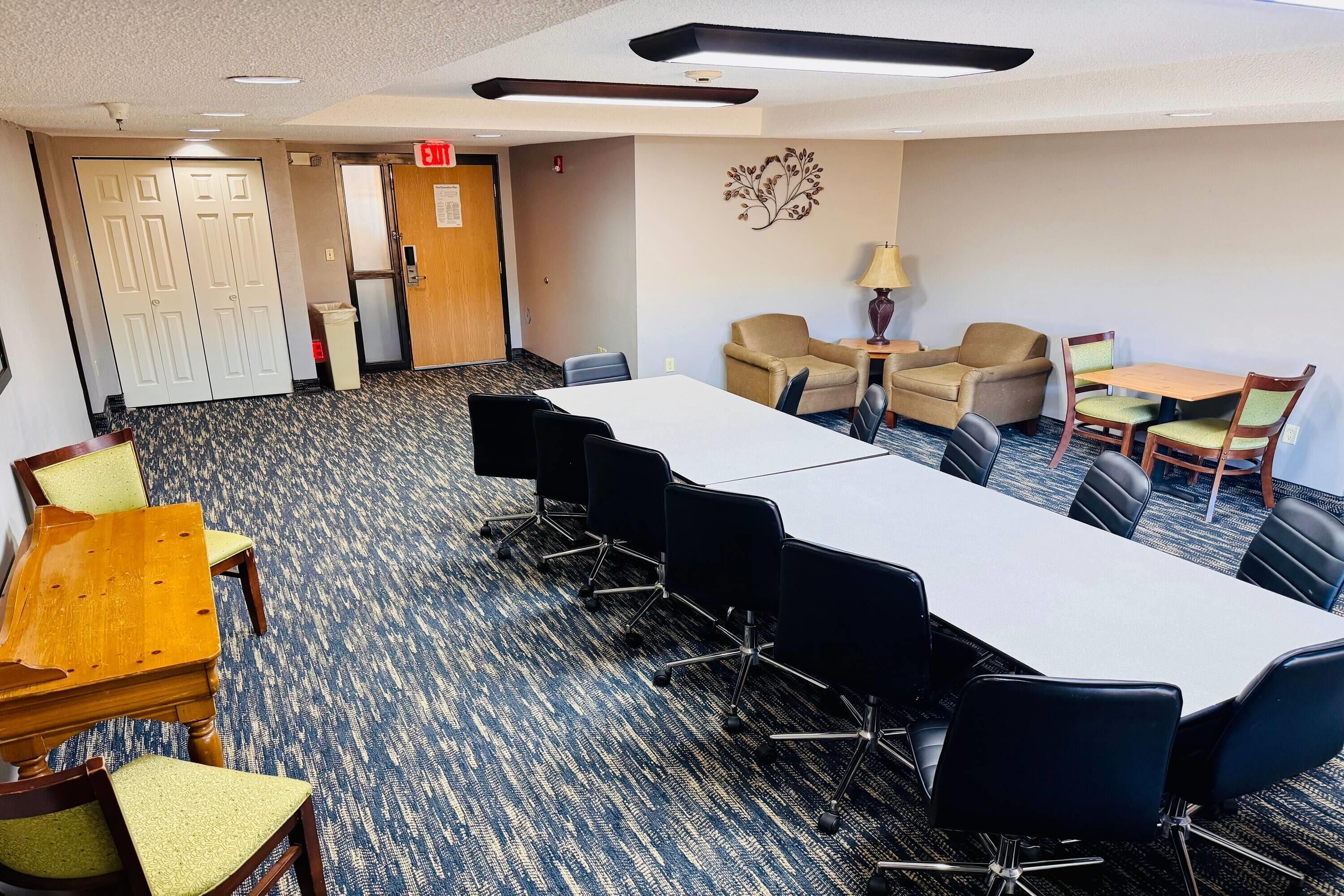 A conference room with a long table, several chairs, a small sofa, and a lamp.