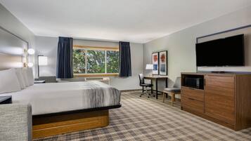 Ein Hotelzimmer mit Bett, Schreibtisch, Stuhl, Fernseher und Kleiderschrank.