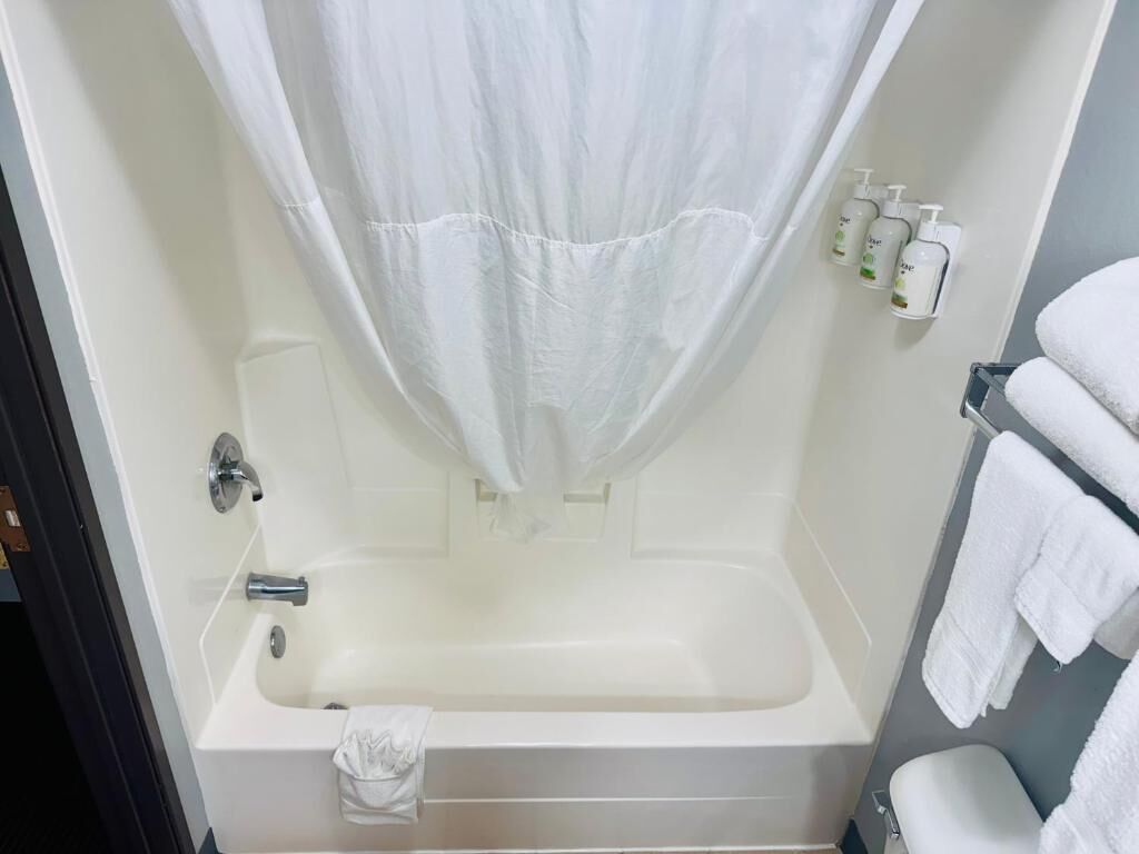 A bathroom with a bathtub, a shower curtain, and a towel rack with towels.